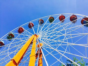 Low angle view of ferris wheel against clear blue sky