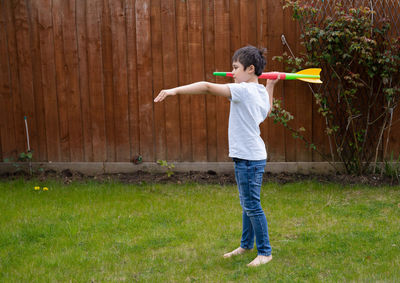 Rear view of man with arms outstretched standing on grassy field