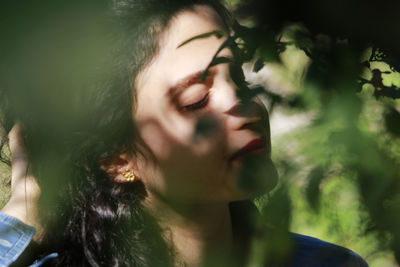 Close-up of young woman with eyes closed standing amidst plants