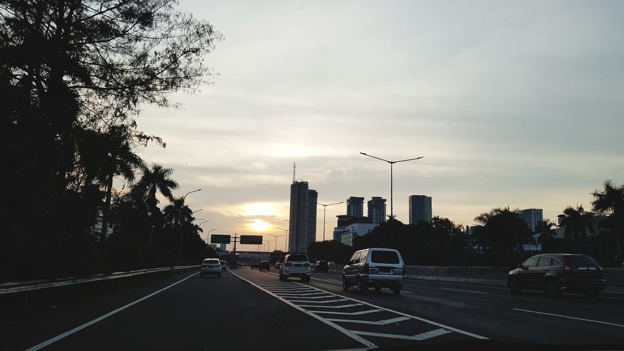 VEHICLES ON ROAD AT SUNSET