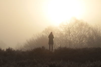 Rear view of man standing on field against sky