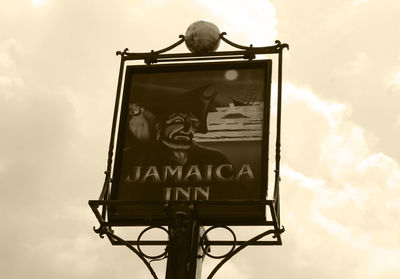 Close-up of sign board against cloudy sky