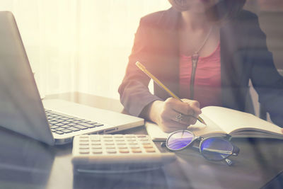 Midsection of woman using mobile phone while sitting on table