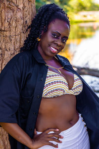 Portrait of smiling woman leaning on tree