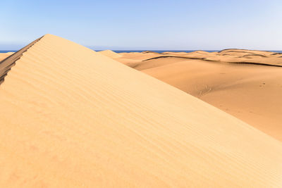Sand dunes in desert against clear sky