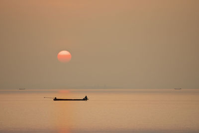 Fisher man and boat in morning with sunrise background