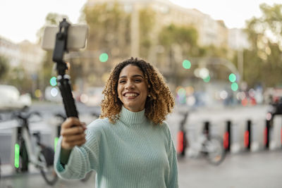 Happy woman filming through smart phone on tripod