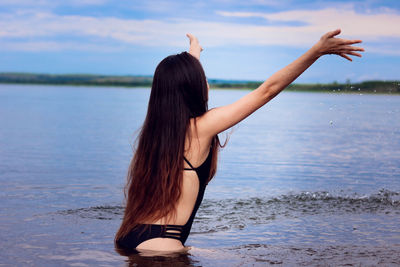 Sensuous young woman standing in sea against sky