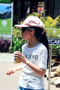 Young woman holding text while standing outdoors