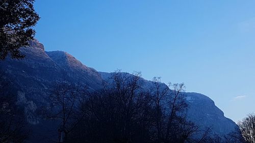 Low angle view of tree mountains against clear blue sky