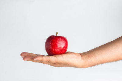 Hand holding apple against white background