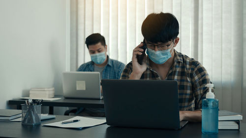 Side view of woman using laptop at office