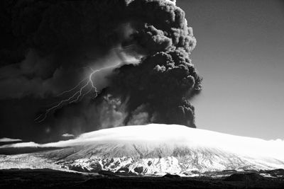 Low angle view of stormy clouds over snowcapped mountain