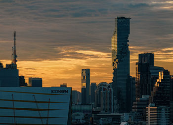 Modern buildings in city against sky during sunset