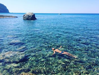 Man swimming in sea against clear sky