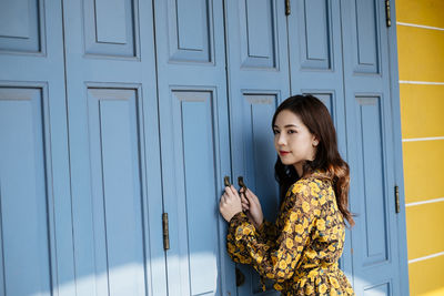 Woman standing against door of building