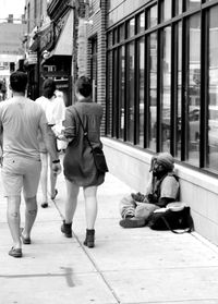 Rear view of people walking on sidewalk