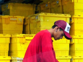 Side view of young man standing against yellow wall