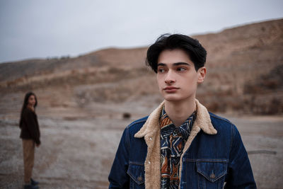 Portrait of young man standing on land against sky