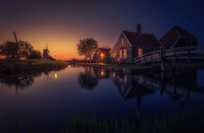 Houses by canal during sunset