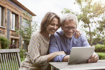 Happy mature couple sharing digital tablet in garden