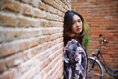 Side view portrait of young woman leaning on brick wall