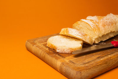Close-up of bread on cutting board against orange background
