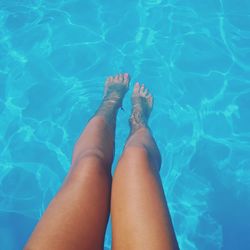 Low section of young woman relaxing in swimming pool