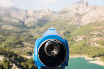 Close-up of coin-operated binoculars against mountain range