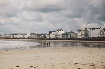 Sea by cityscape against sky