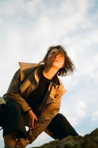 Low angle view of woman sitting against sky