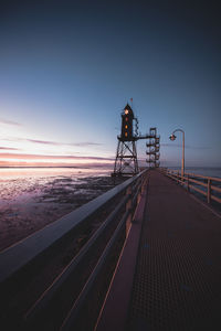 Railroad tracks by sea against sky during sunset