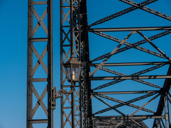 Low angle view of electricity pylon against blue sky