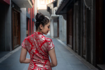 Girl standing against red building