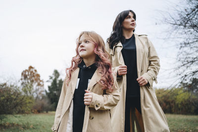 Girl and mother wearing trench coat at park