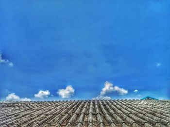 Low angle view of roof tiles on field against blue sky