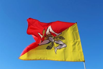 Low angle view of flag against clear blue sky