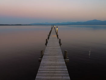 Wooden pier over lake against sky during sunset