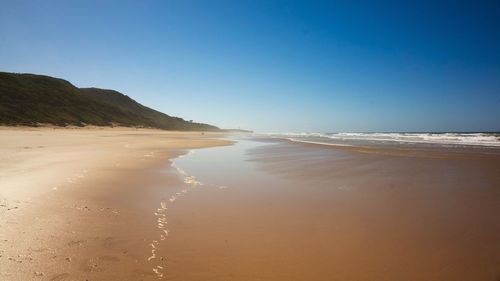 Scenic view of beach against clear blue sky