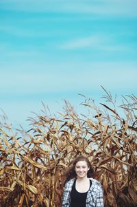 Portrait of happy teenager against crops on field