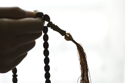 Close-up of hand holding chain against sky