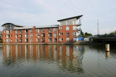 Building by river against sky in city