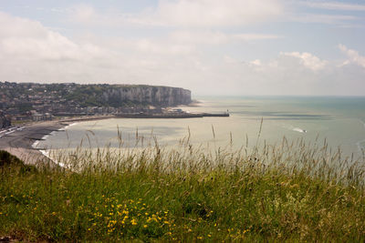 Scenic view of sea by cityscape against sky