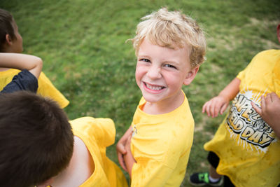 Happy blonde boy smiles at camera while standing in line outdoors