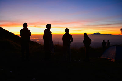 Silhouette people looking at sunset