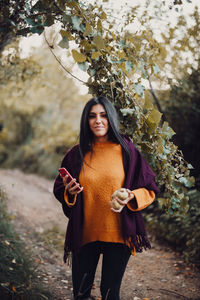 Young woman standing against trees