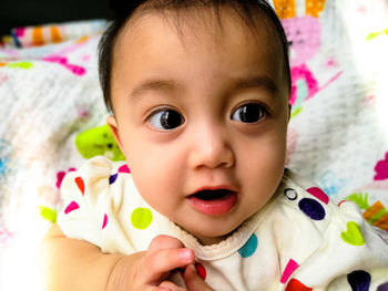 Portrait of cute baby girl lying on bed