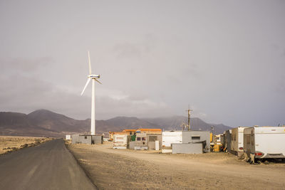 Windmill on road against sky