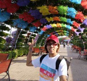 Portrait of boy standing against multi colored umbrella