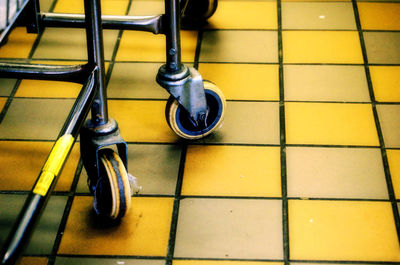 Close-up of cropped shopping trolley on tiled floor